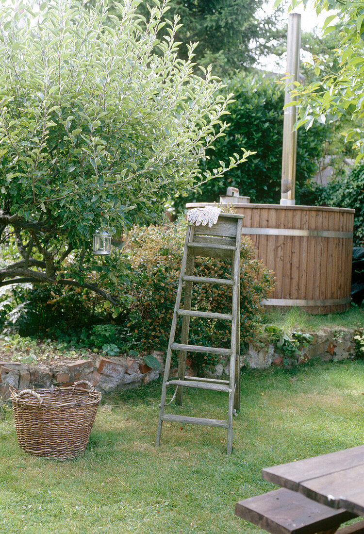 Eine rustikale Holztreppe im Garten neben einem Weidenkorb und einem Obstbaum