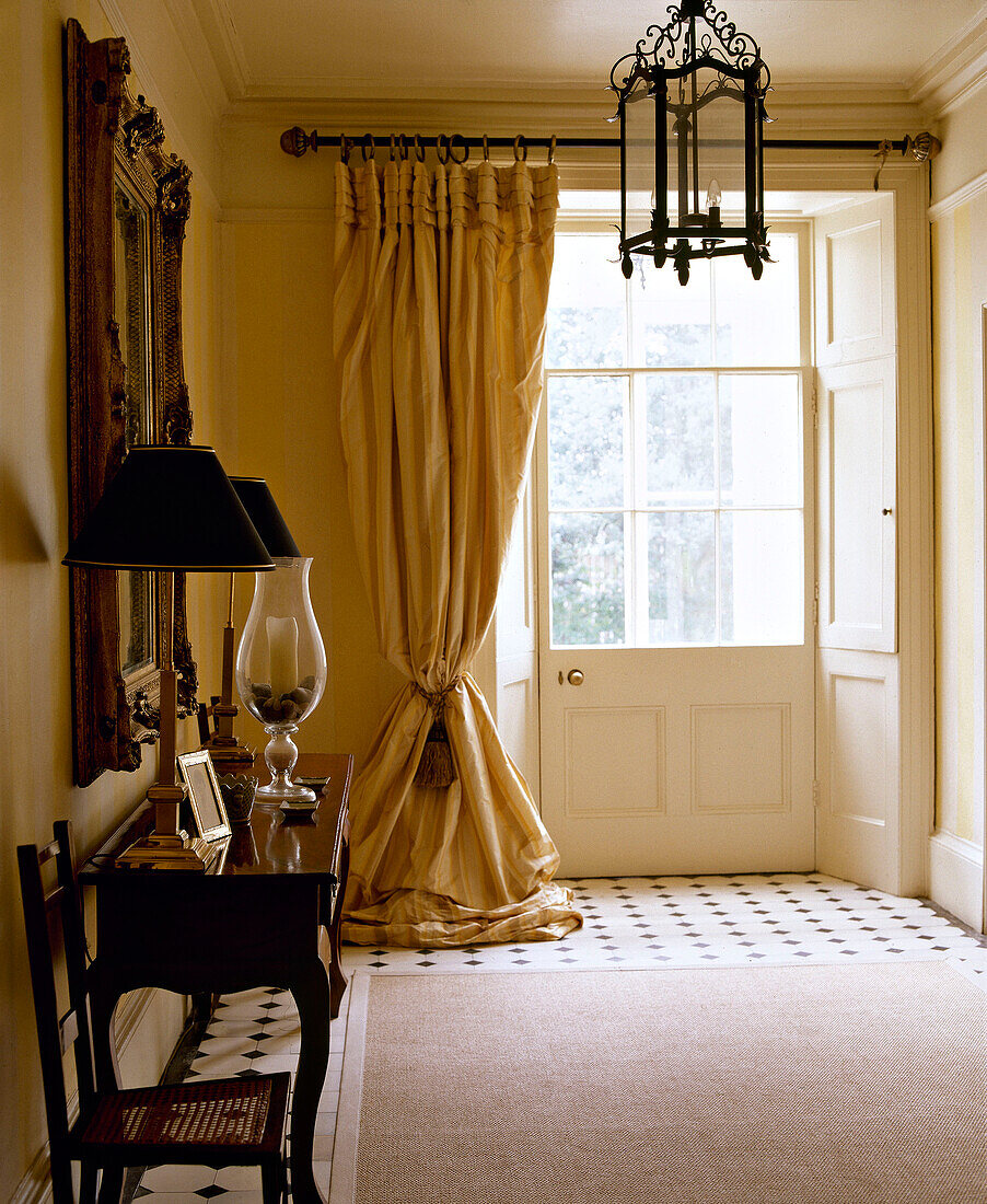 Lantern hanging in hallway above rug at front door with curtain