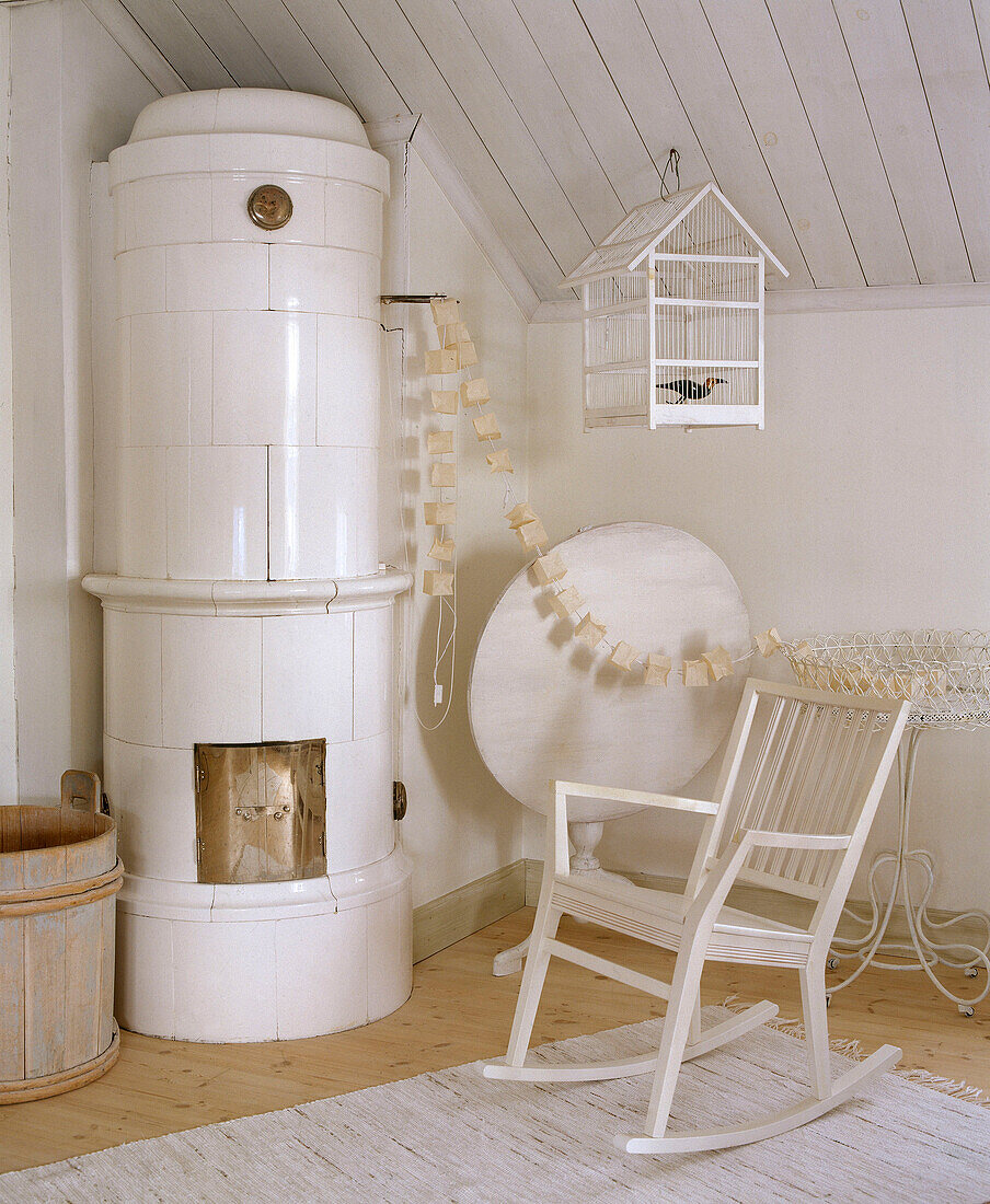 White wood rocking chair next to traditionally Scandinavian tiled wood burning stove