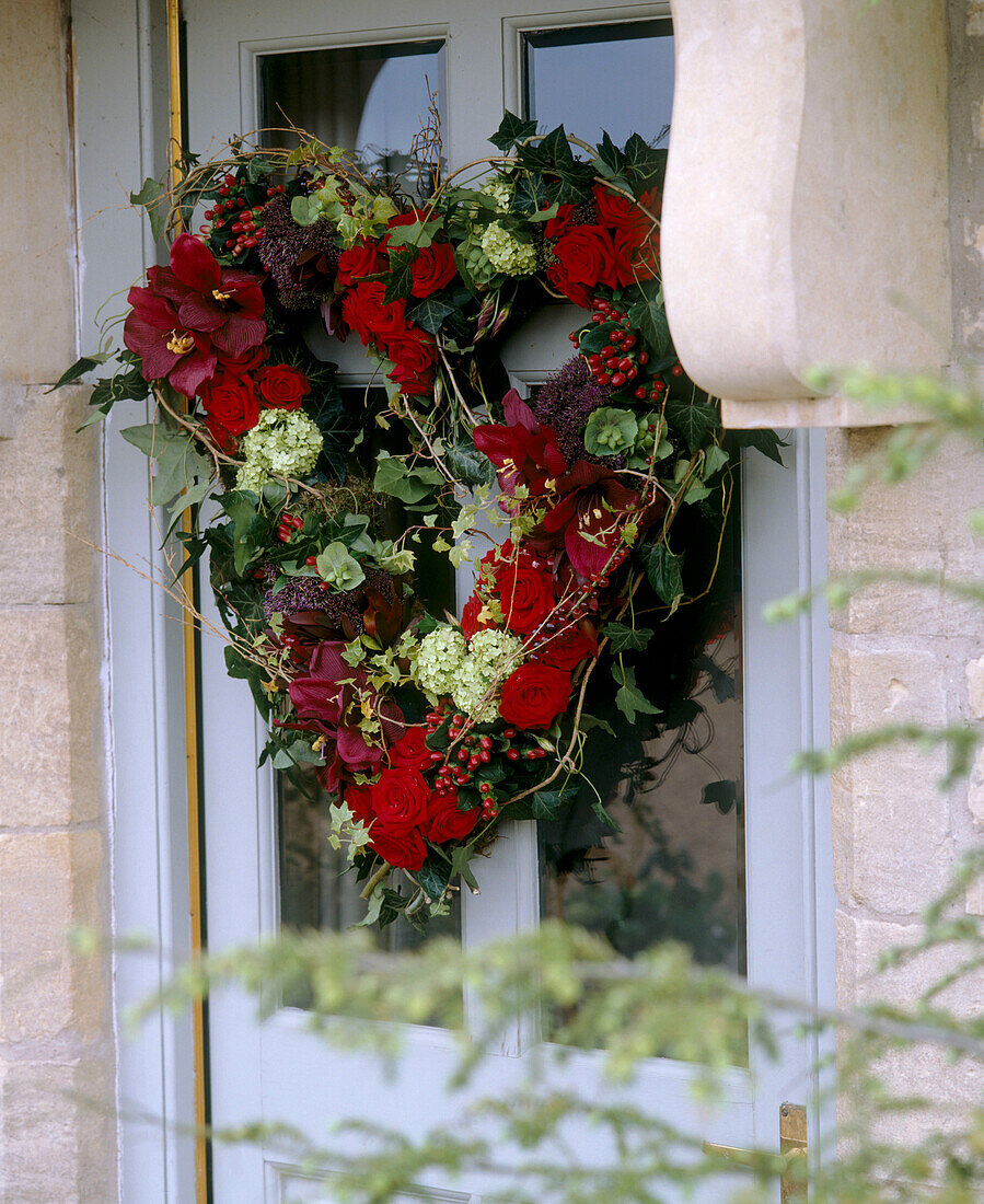 Traditioneller Weihnachtskranz aus Blumen, der an einer Haustür angebracht ist