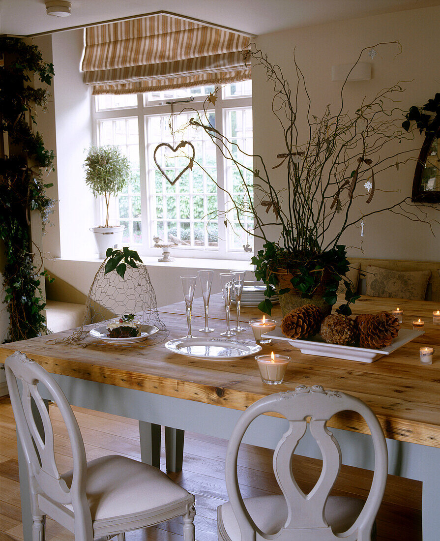 A traditional dining room with a wooden table and chairs featuring a display of plants and pine cones