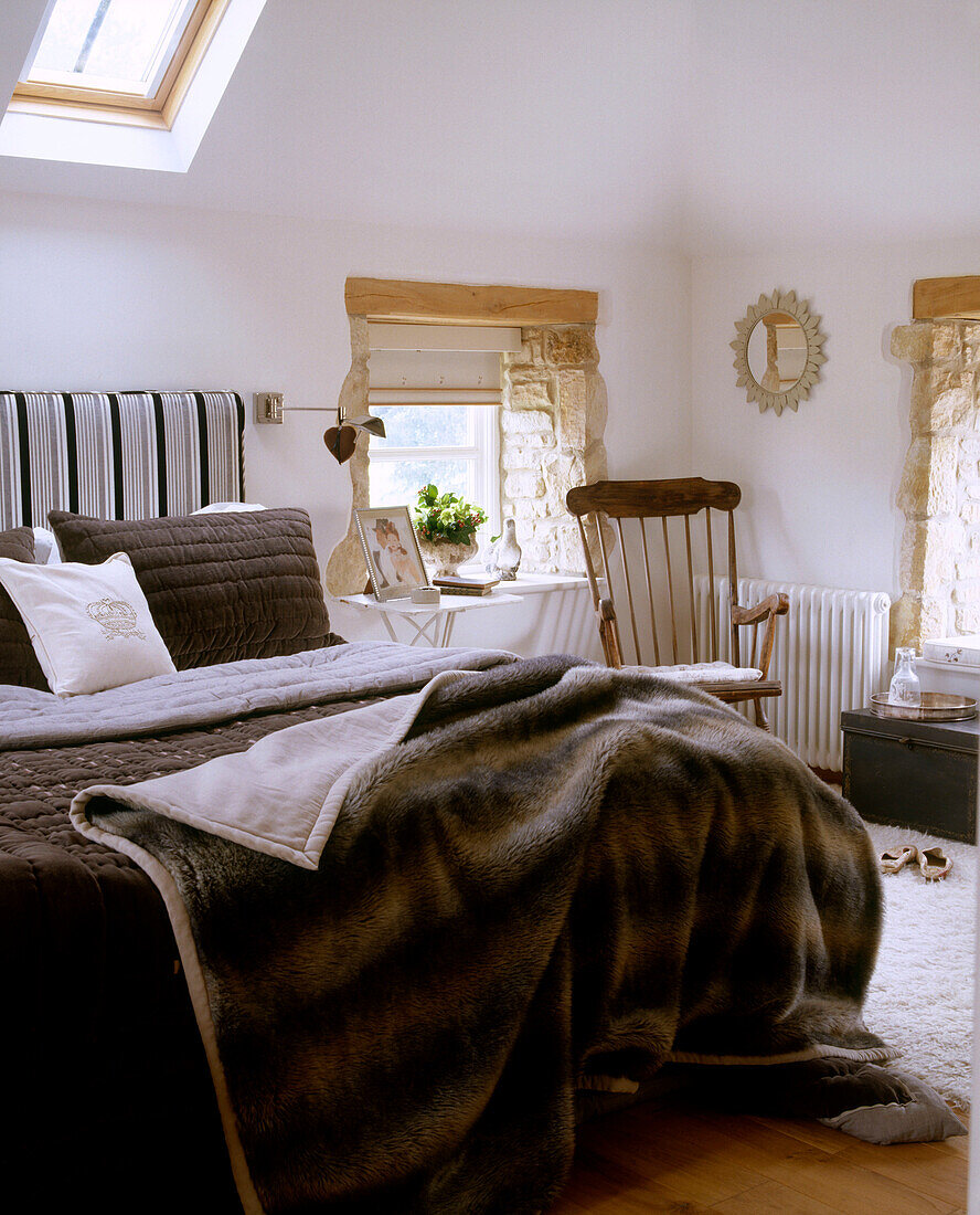 Ein traditionelles Schlafzimmer mit einem Oberlicht in einer Dachschräge über einem mit Fell bezogenen Bett