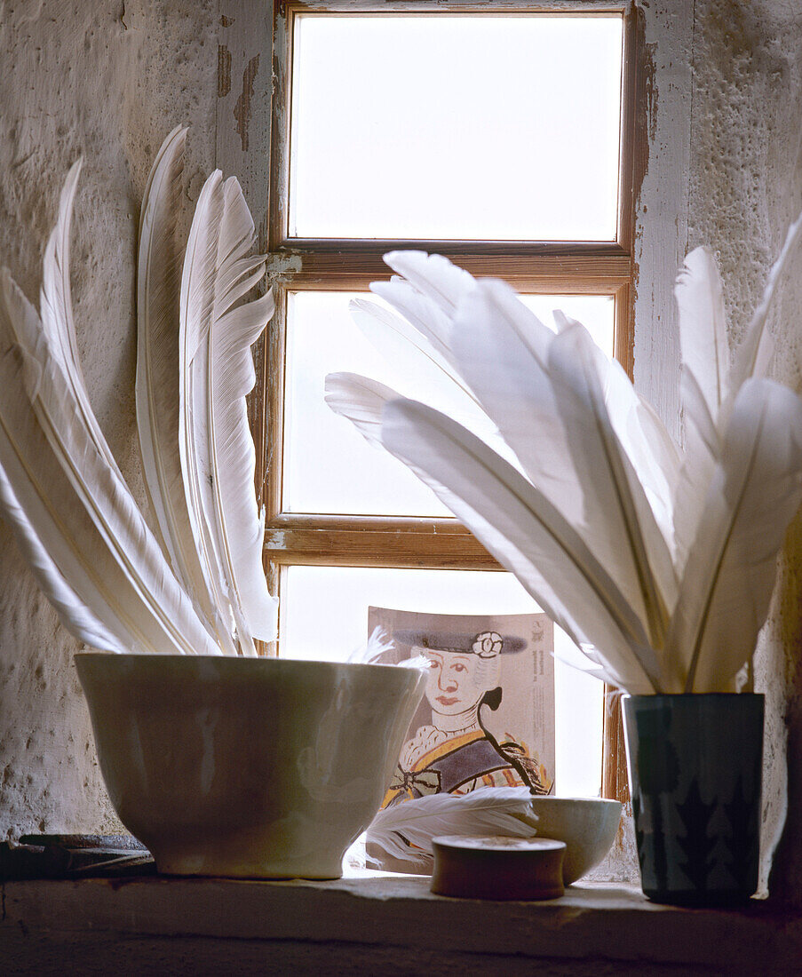 Feathers in a bowl on stone window sill