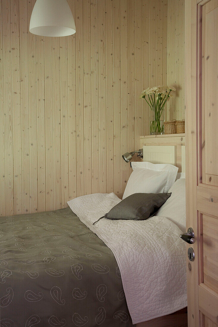 View through open door to double bed in wood panelled bedroom