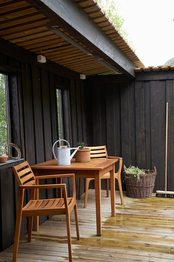Holztisch und Stühle auf einer überdachten Veranda