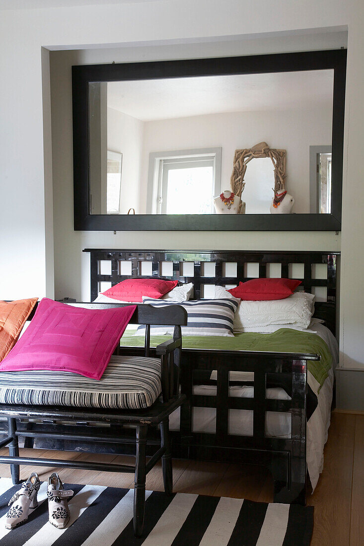 Mirror above contemporary double bed with pink cushions