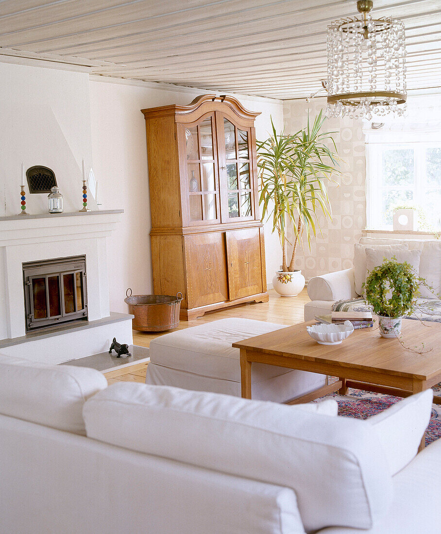 Weißes Wohnzimmer mit Kamin und getäfelter Decke in Mjolby, Schweden
