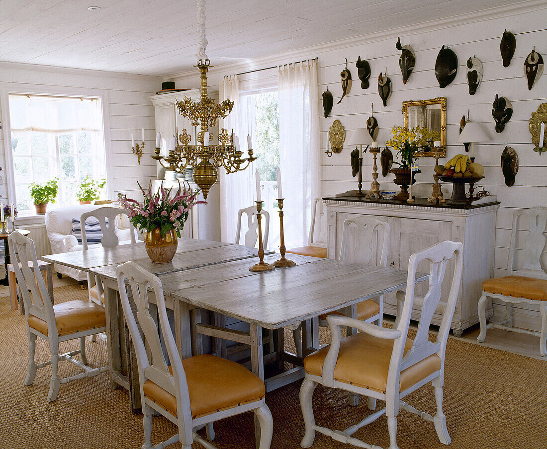 Holztisch und gustavianische weiße Holzstühle in einem Esszimmer im Landhausstil