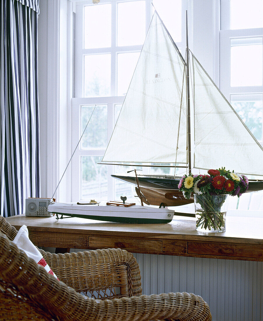 Korbstuhl vor einer Fensterbank mit Modellboot