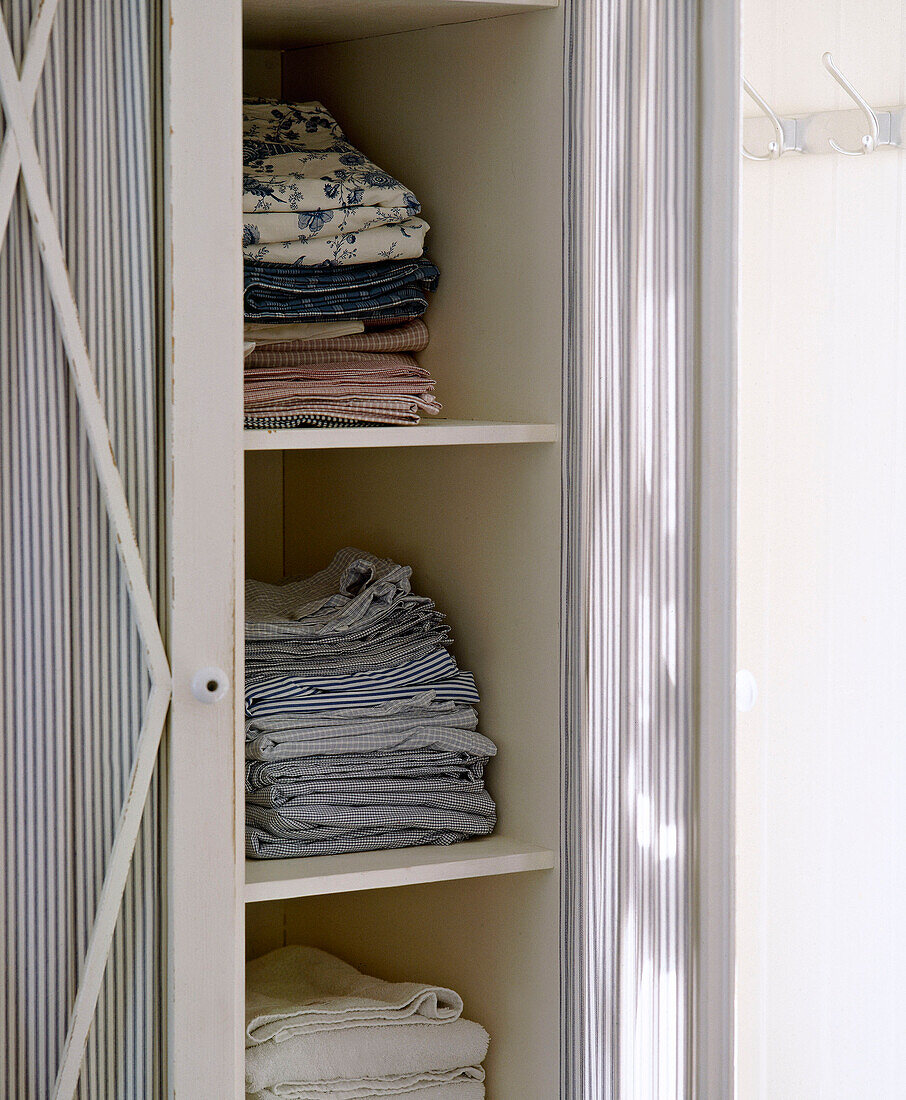 Folded linen in white wood cupboard