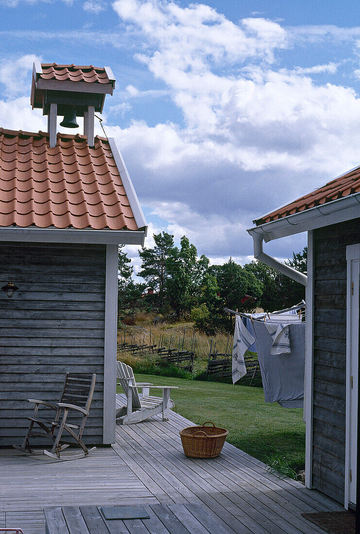 Holzstuhl auf einer Terrasse mit Wäscheleine auf der Wiese