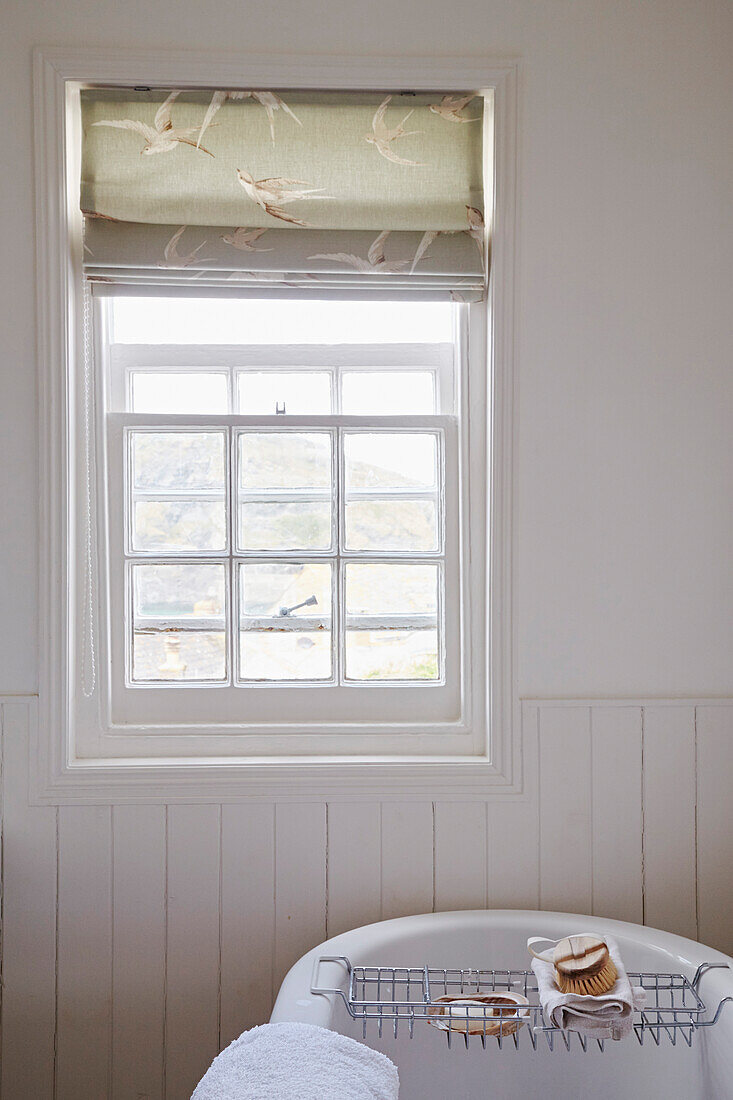 Raffrollos am Fenster im weiß getäfelten Badezimmer des Strandhauses von Port Issac in Cornwall