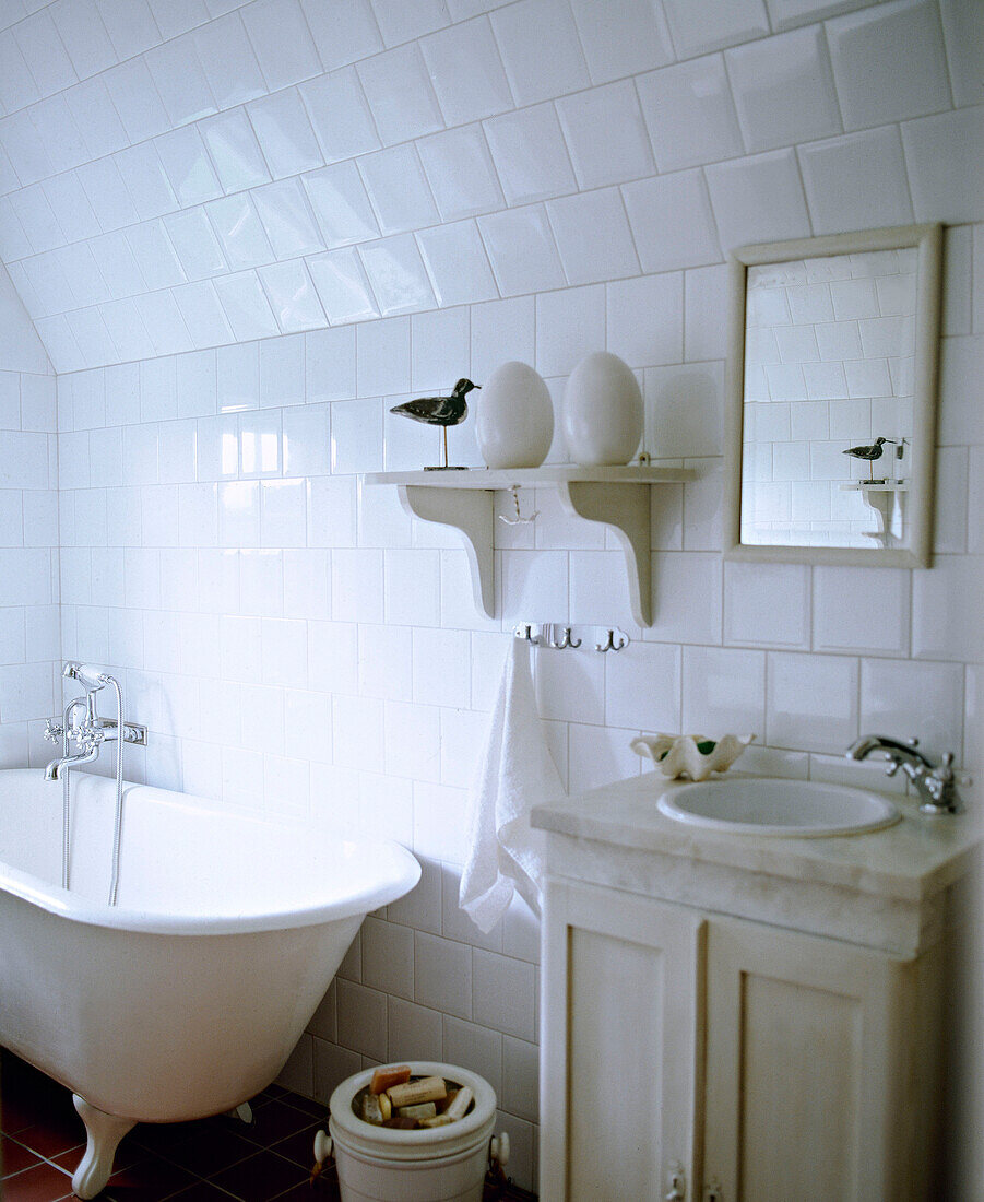 Waschbecken in einem Schrank mit Marmorplatte neben einer freistehenden Badewanne mit Rollen