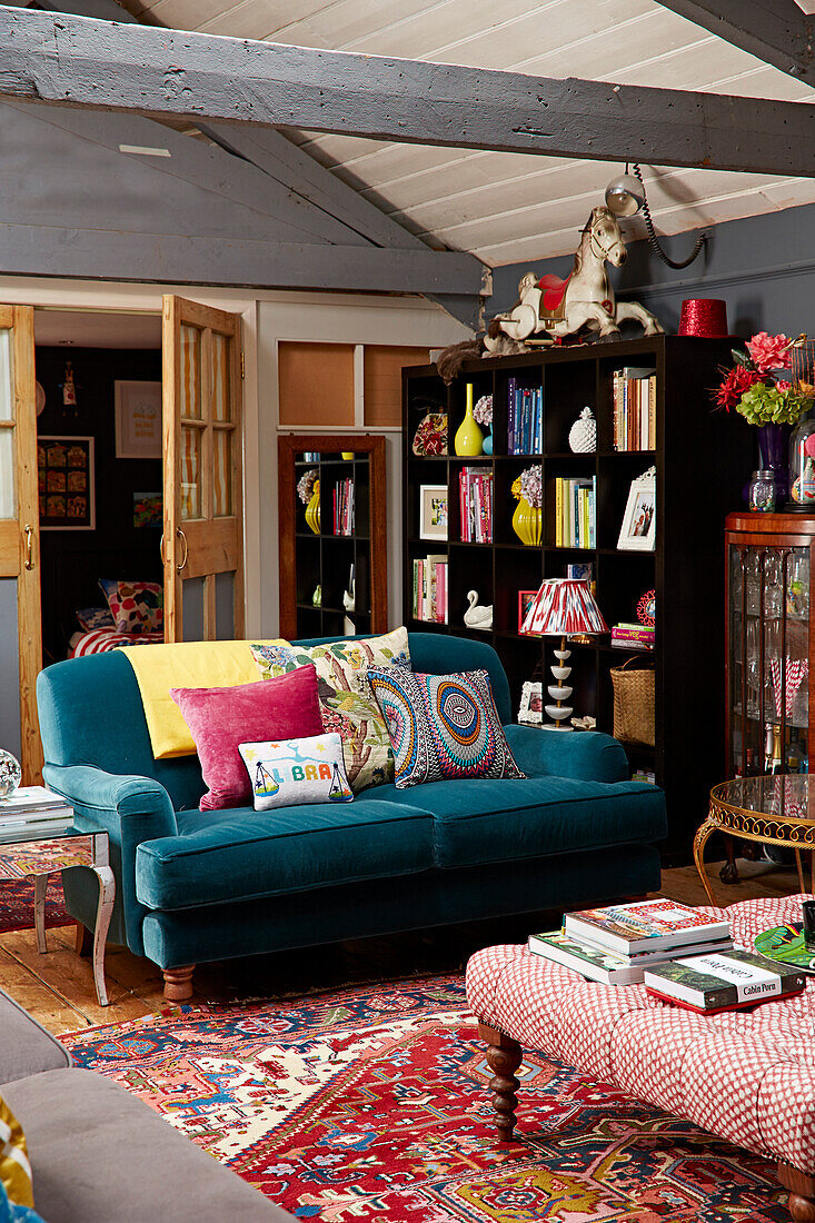 Tealfarbenes Sofa und Bücherregal in einer umgebauten Scheune in Brighton, East Sussex UK