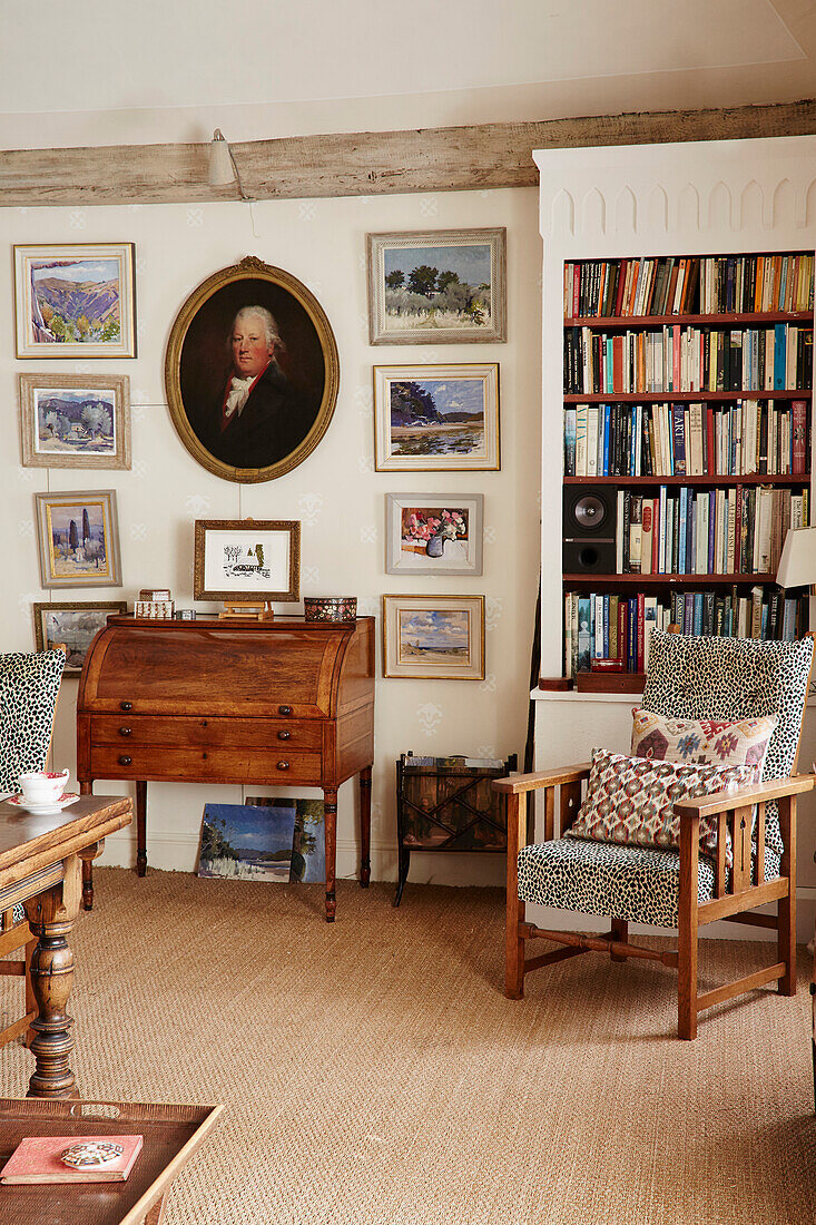 Gerahmte Bilder, Bücherregal, antike Kommode und Polsterstuhl in einem Haus aus dem 17. Jahrhundert in Hampshire, England, UK