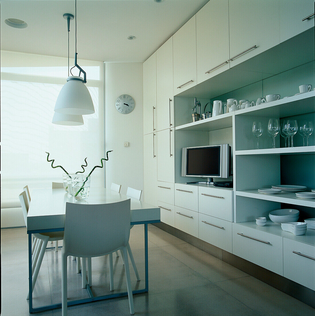 Contemporary white kitchen diner with large wall storage unit for tableware and home wares