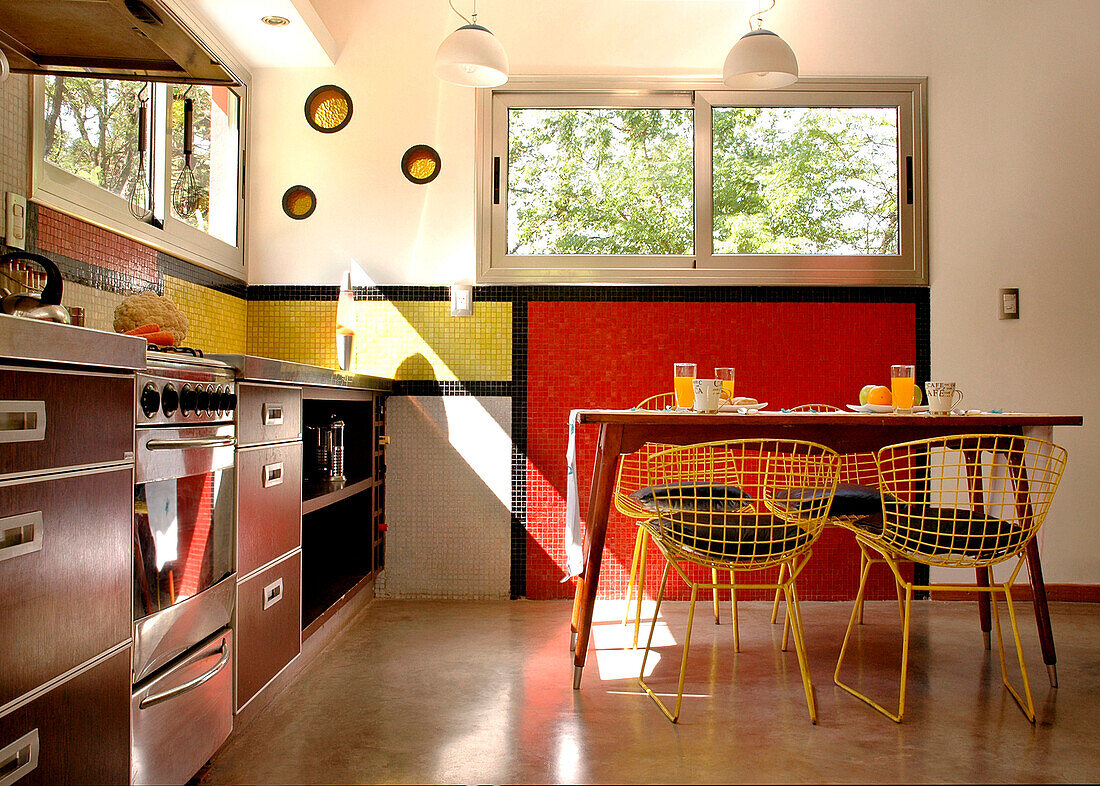 Der Fußboden der Küche ist aus geglättetem Beton, und an den Wänden, die mit perfekt geometrischen Fliesen bedeckt sind, und an den kleinen runden gelben Fenstern kommt die Farbe wieder zum Vorschein - ein Merkmal, das den Designer dieses erstaunlichen Hauses charakterisiert