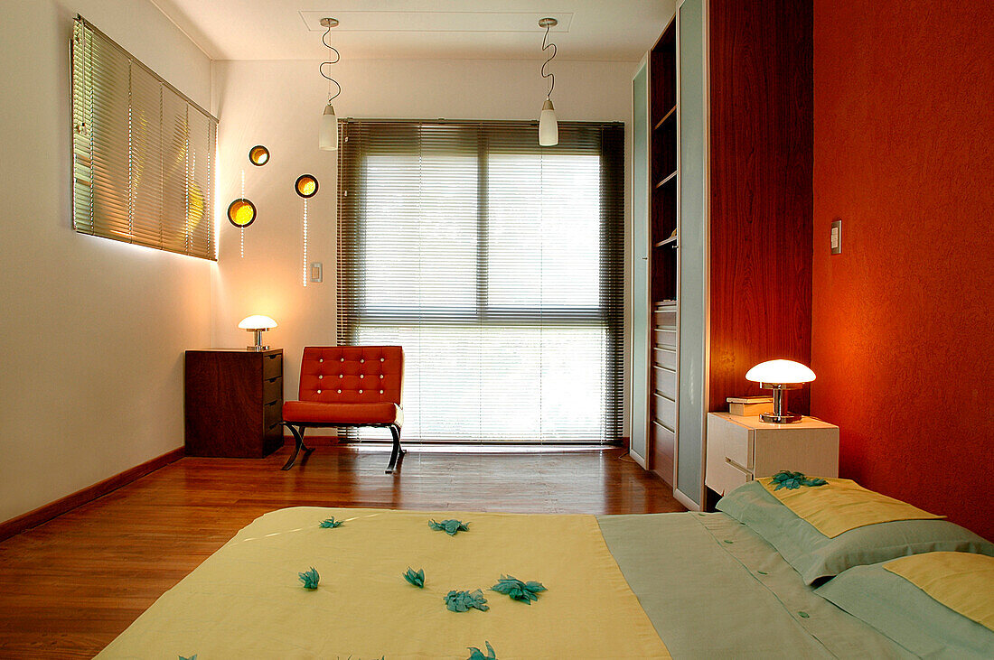 Matratze auf Kiefernholzboden mit Nachttisch, Lampen vom Flohmarkt und runde Fenster im Architektenstil