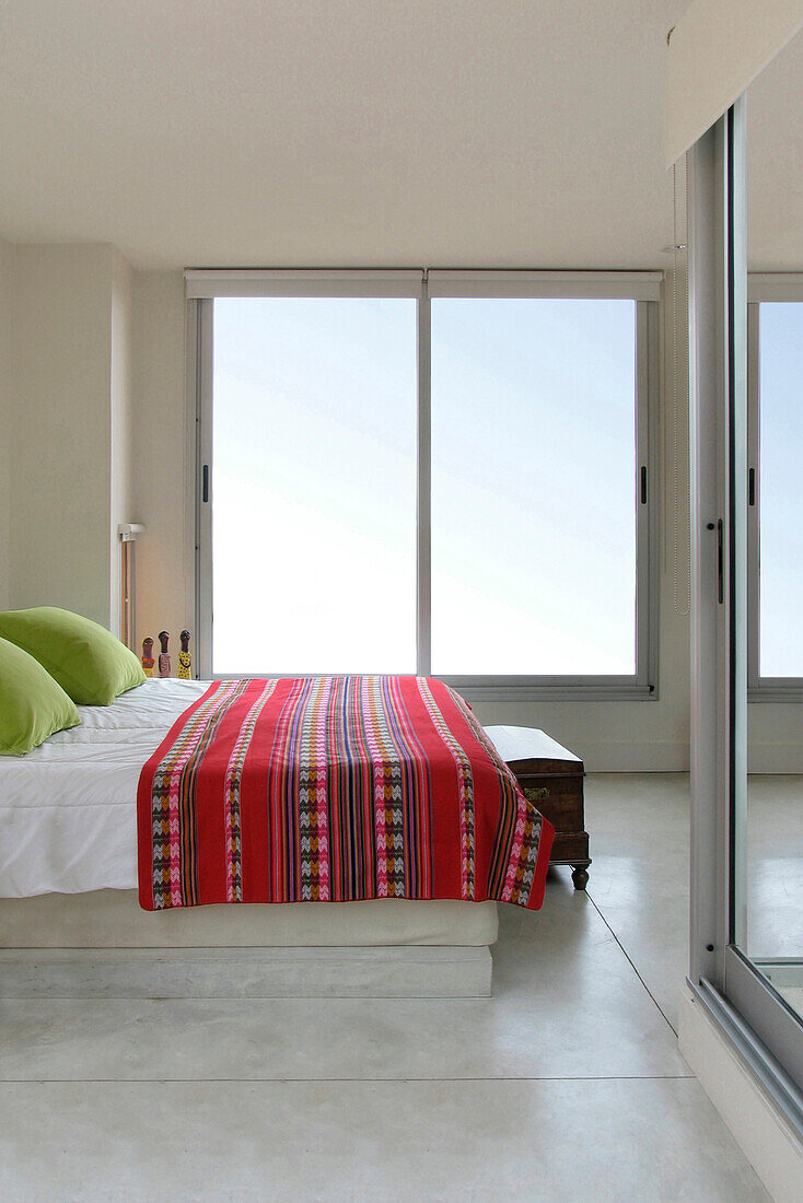 Bett mit bestickter Decke, lindgrünen Kissen und Schiebetüren