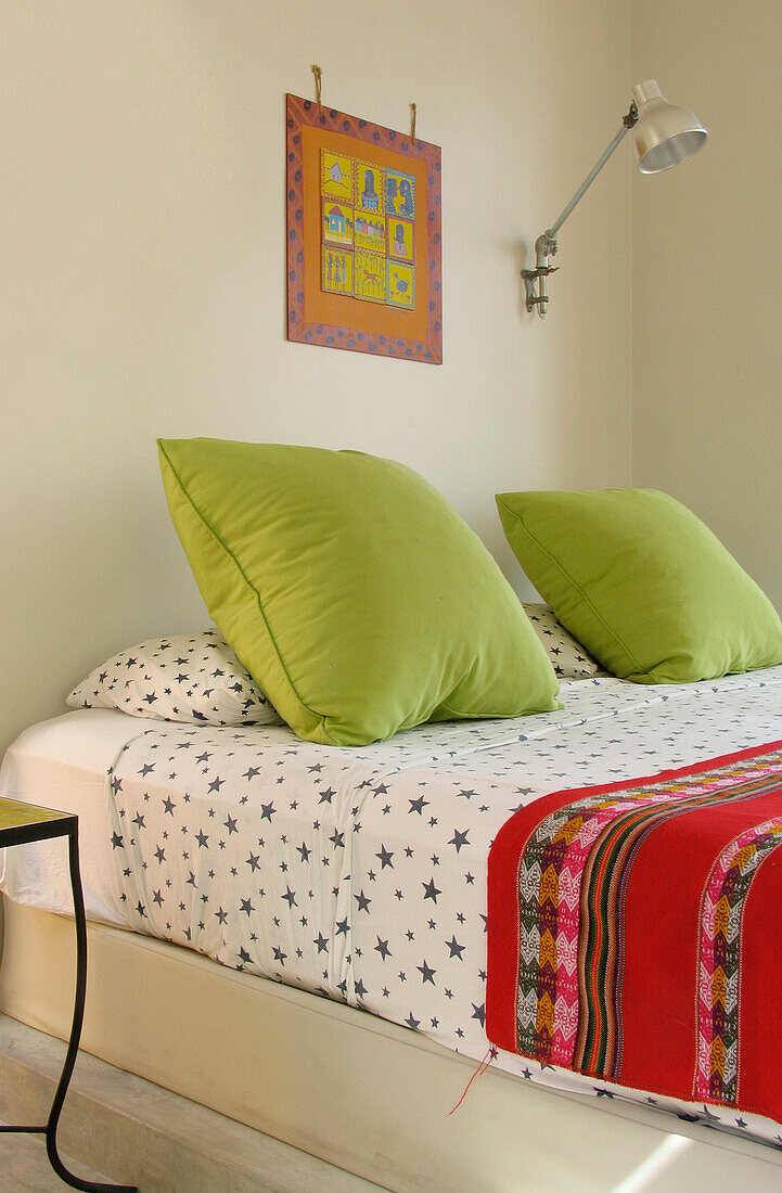 Schlafzimmer mit lindgrünen Kissen und gemustertem Bettbezug