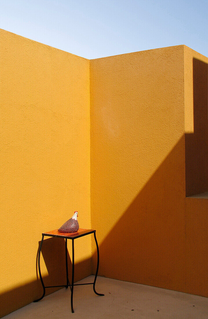 Orange gestrichene Wände einer Außenterrasse mit Tisch