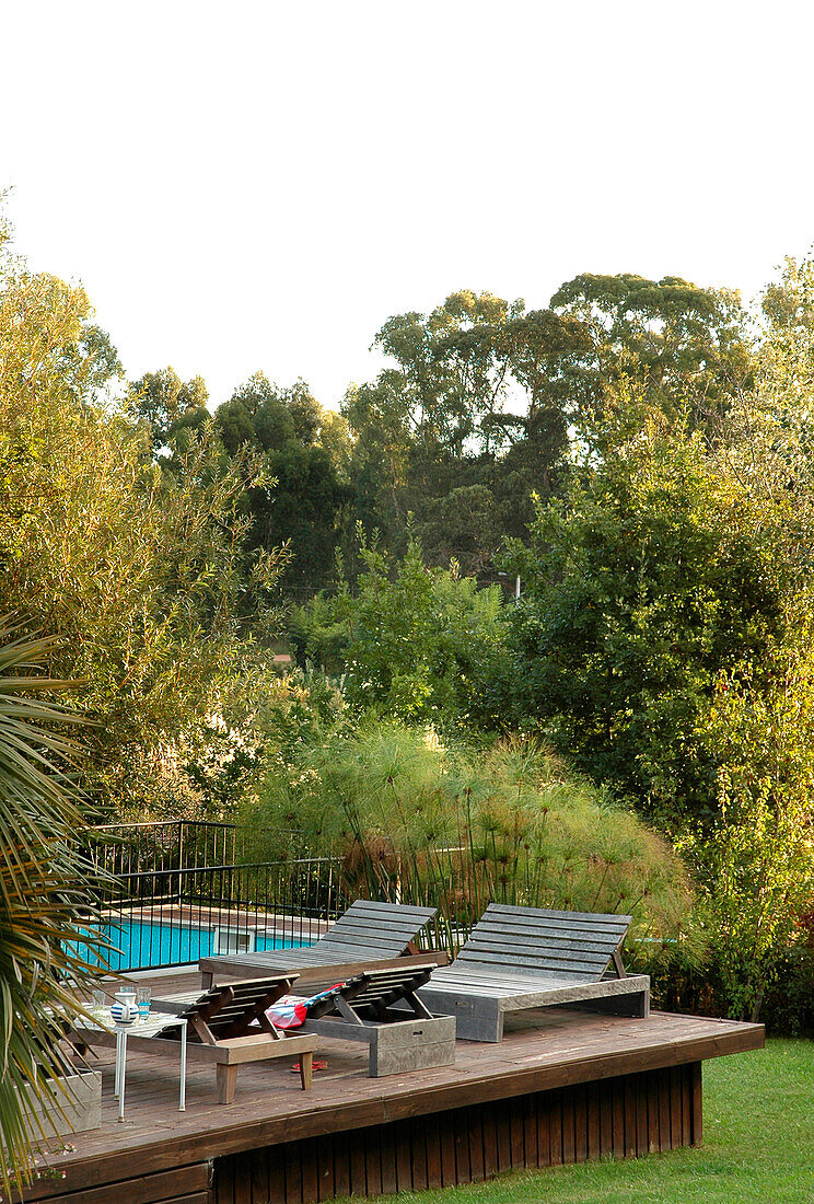 Sun loungers on poolside decking in woodland setting