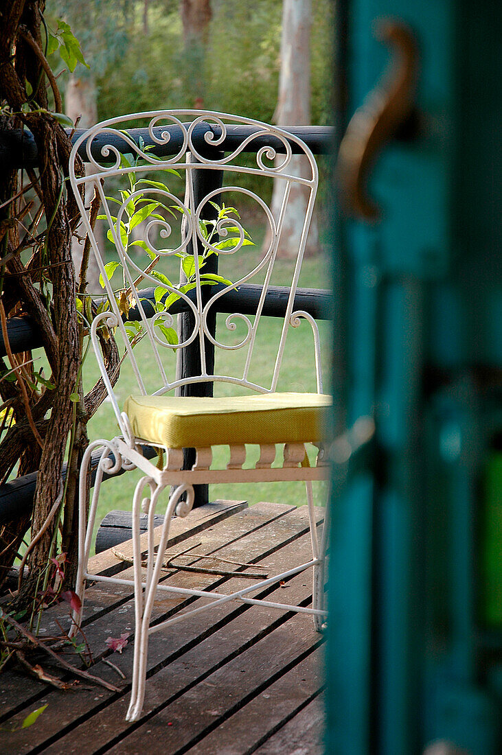 Wrought iron white painted chair view through back door of garden terrace