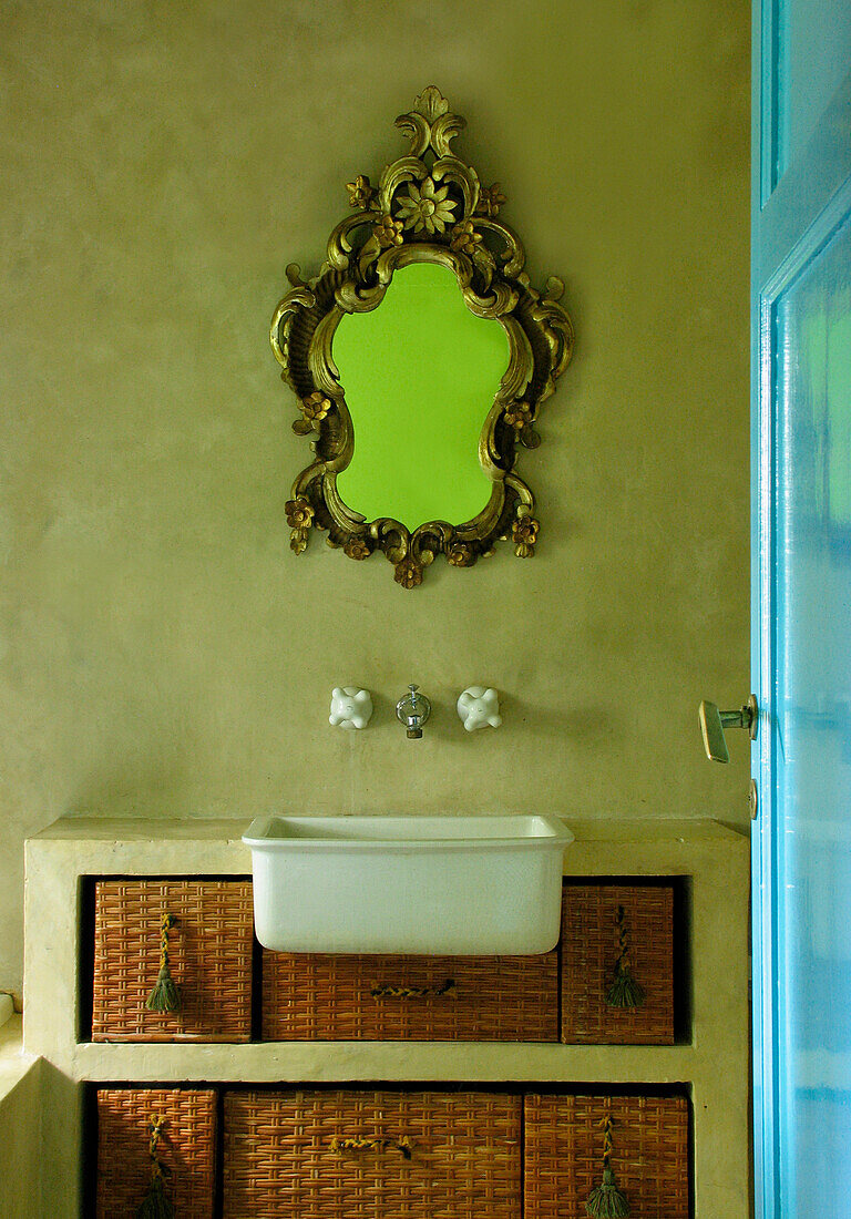Spiegel mit vergoldetem Rahmen über Waschtisch mit Rattankörben