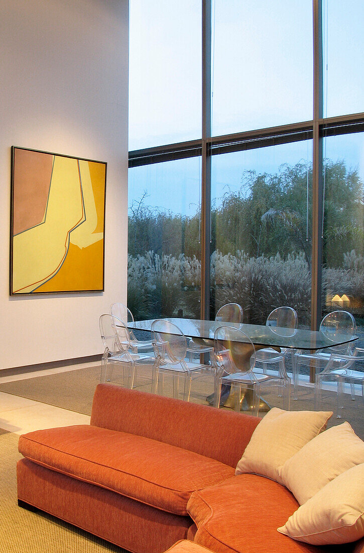 Essbereich mit Plexiglastisch und Stühlen, Sofa mit Terrakotta-Stoffbezug und Kunstwerk von Alberto Carbi