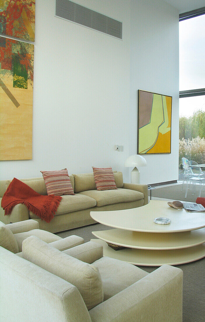 Sitzbereich mit einem mit neutralem Stoff bezogenen Sofa und einem Kunstwerk von Alberto Carbi