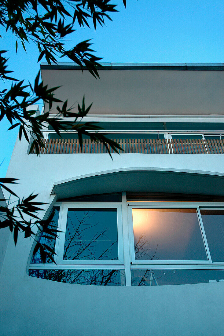 Moderne Stuckfassade mit weißem Aluminium und augenförmigen Fenstern