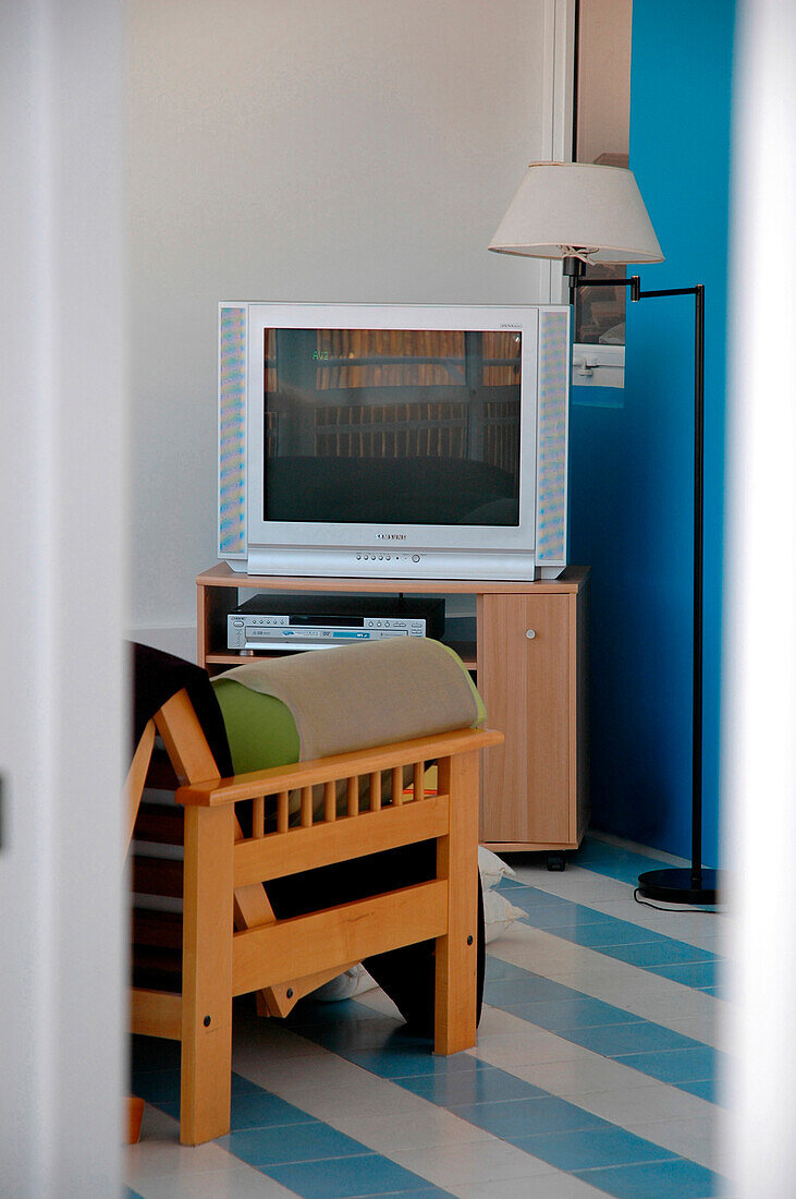 Television and chair in living room with turquoise walls