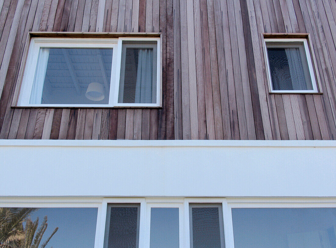 Windows of holiday home exterior with wood cladding