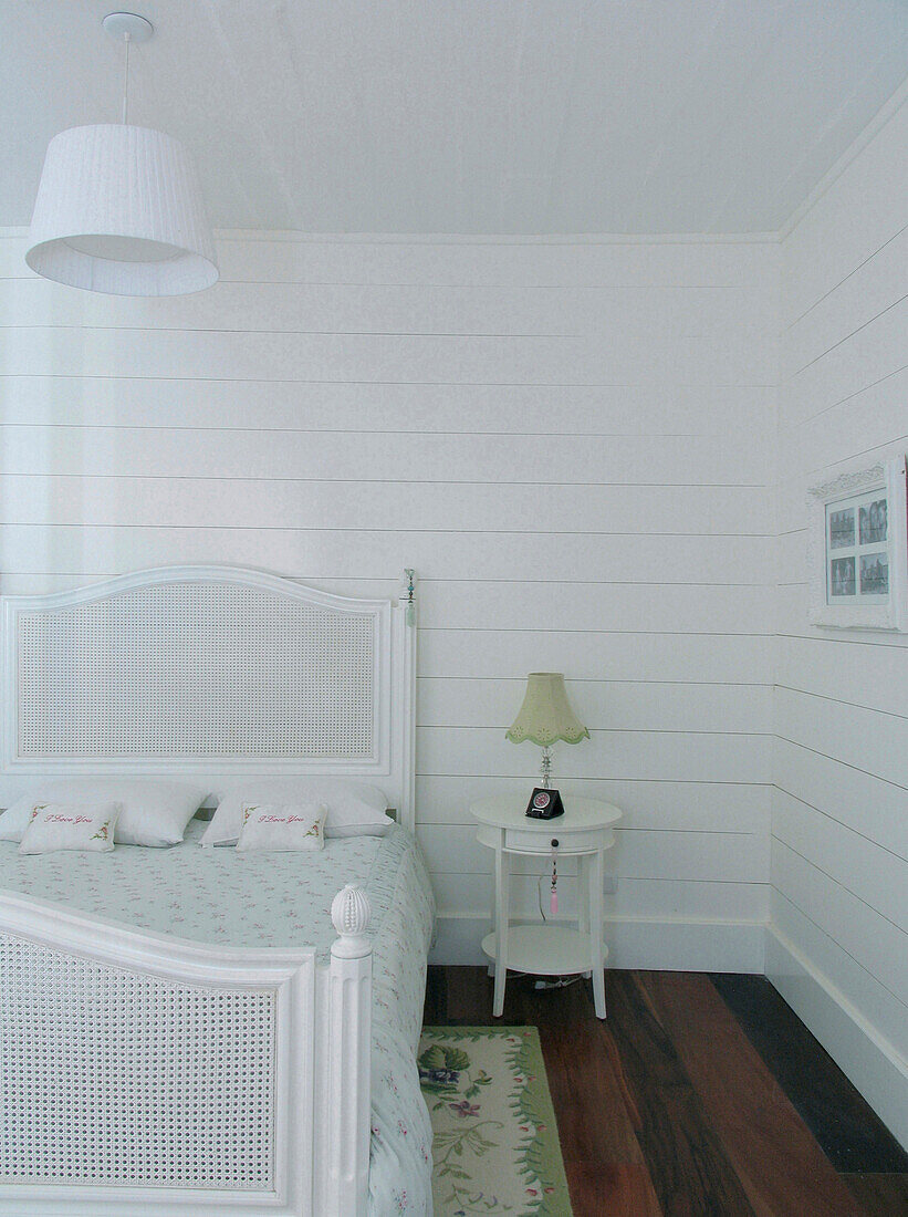 Weiß gestrichenes Schlafzimmer mit dunklem Holzboden