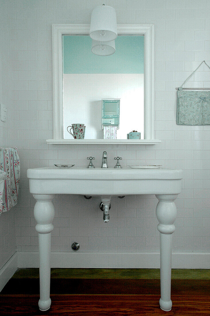 Washstand below mirror in white tiled bathroom