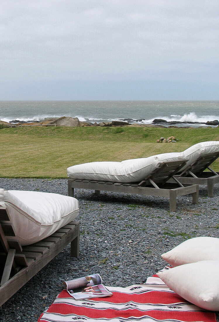Coastal beach house exterior sun loungers on gravelled patio
