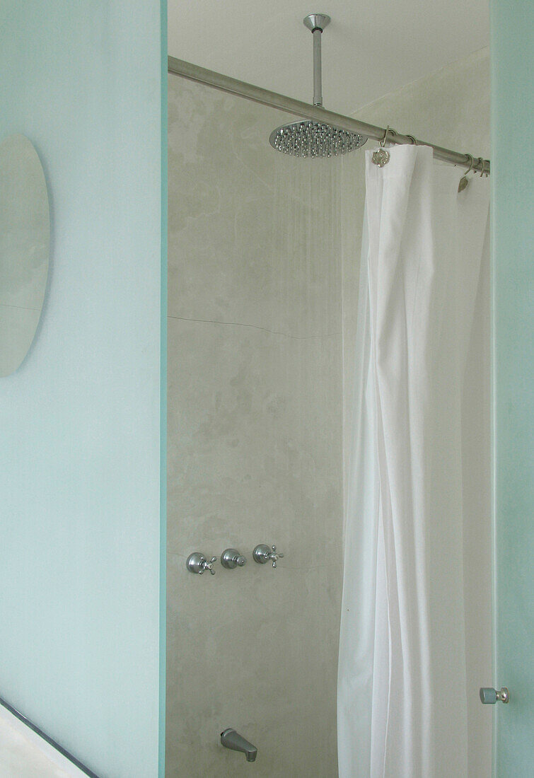 Duschkabine mit Metallduschkopf und weißem Duschvorhang