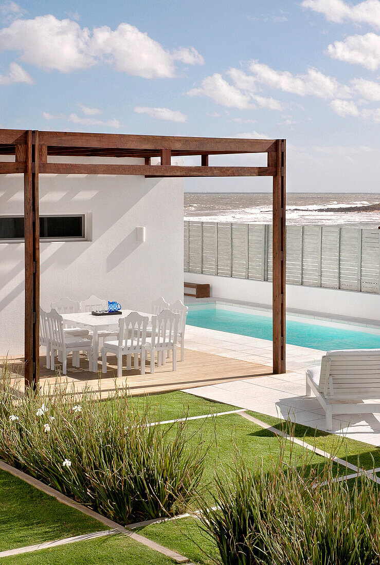 Eating area and swimming-pool with garden furniture and grass with lineal drawings in Lapacho wood