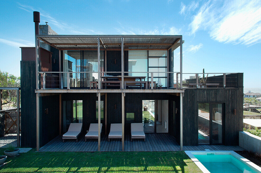 Beach house exterior with shaded balcony and poolside area