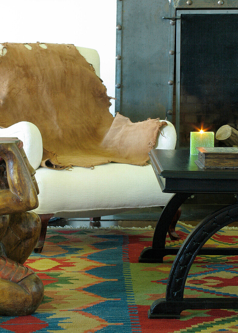 Tierfell auf einem Stuhl neben dem Kamin mit gemustertem Teppich