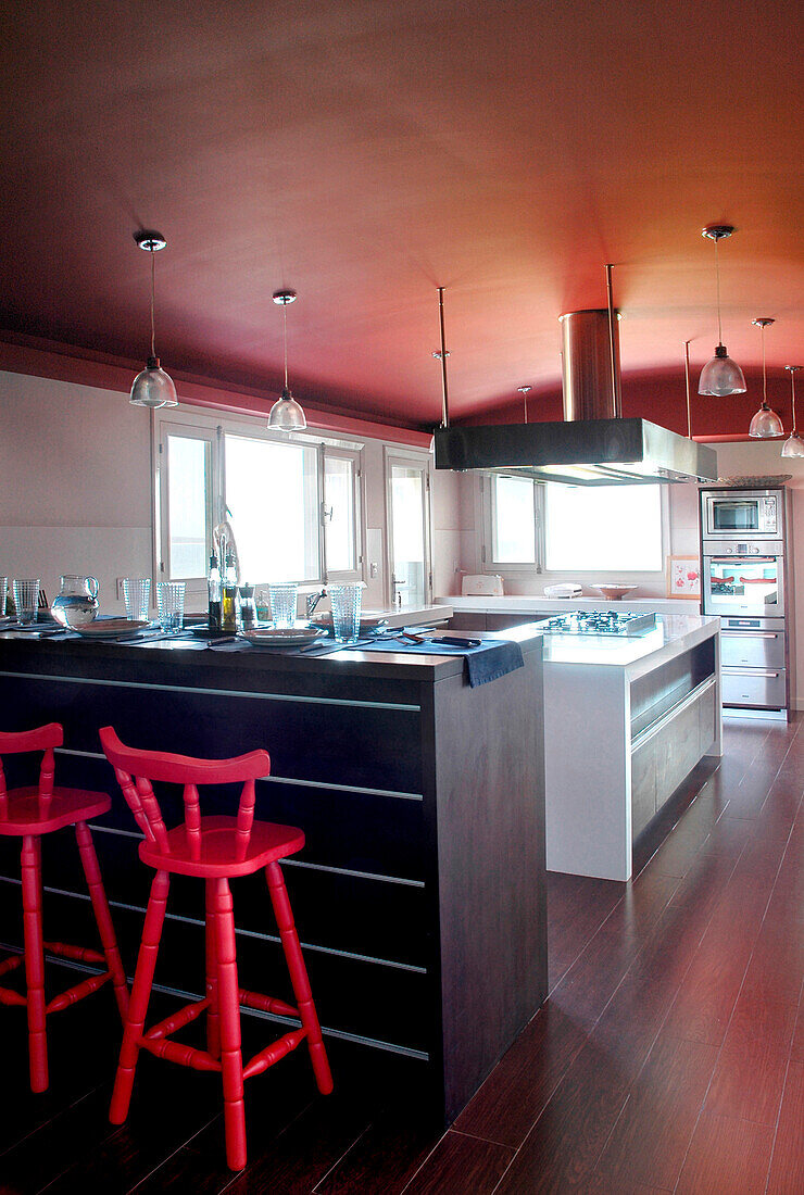 Kitchen with red ceiling and bar stools at counter