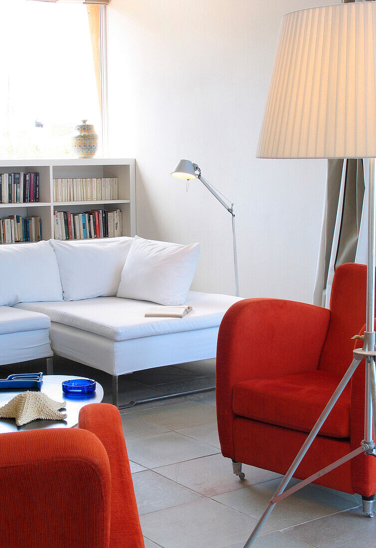 Passende rote Sessel in gefliestem Raum mit Bücherregal und Ecksofa