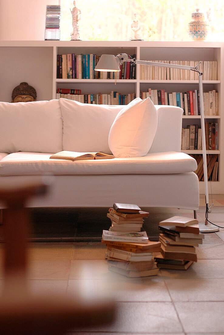 Schreibtischlampe beleuchtet offenes Buch auf weißem Sofa