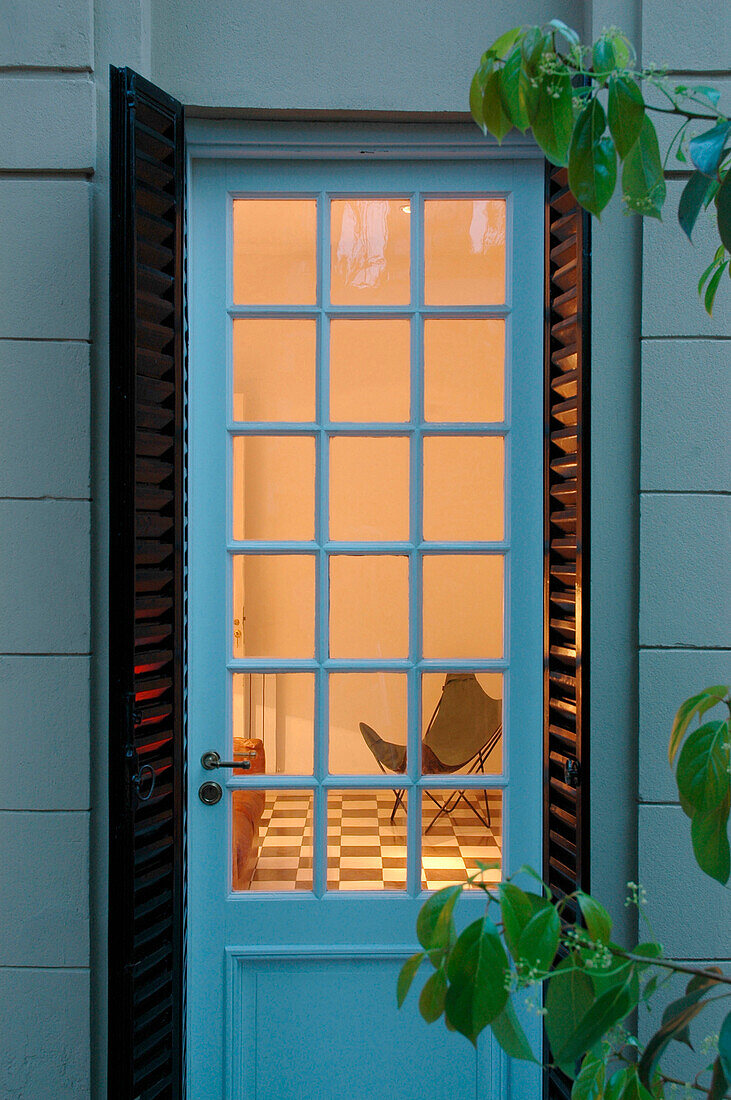Blick durch die Hintertür auf einen beleuchteten Raum mit gefliestem Boden und Stuhl