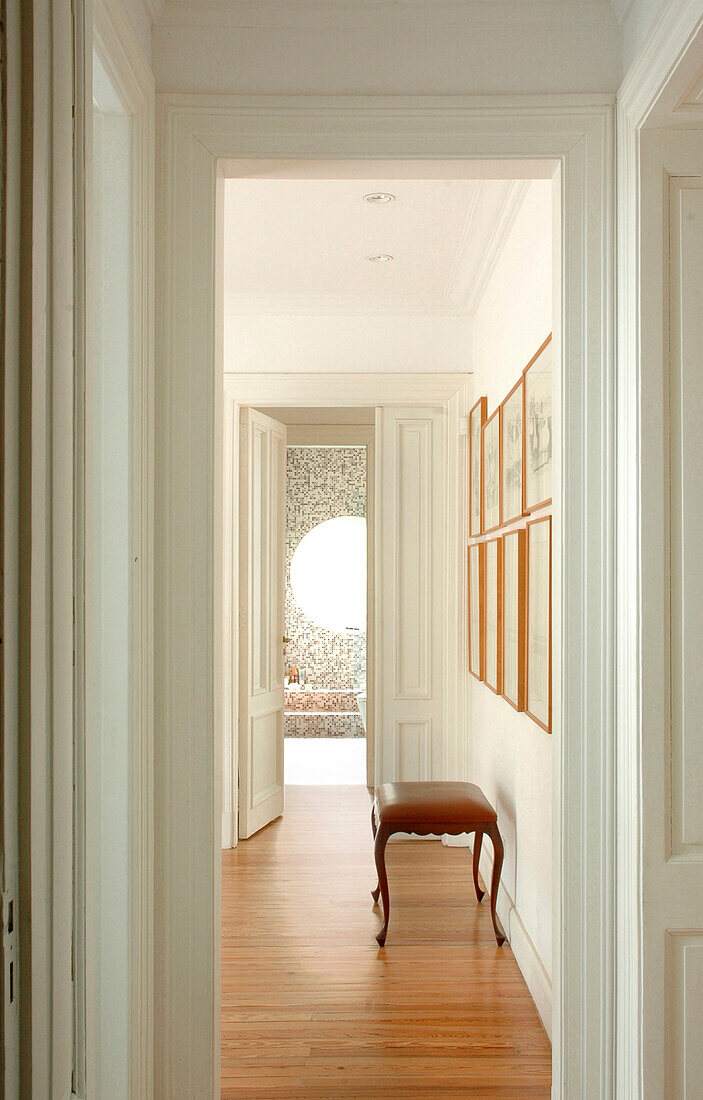 Corridor hallway with stool and artwork viewed though doorframe