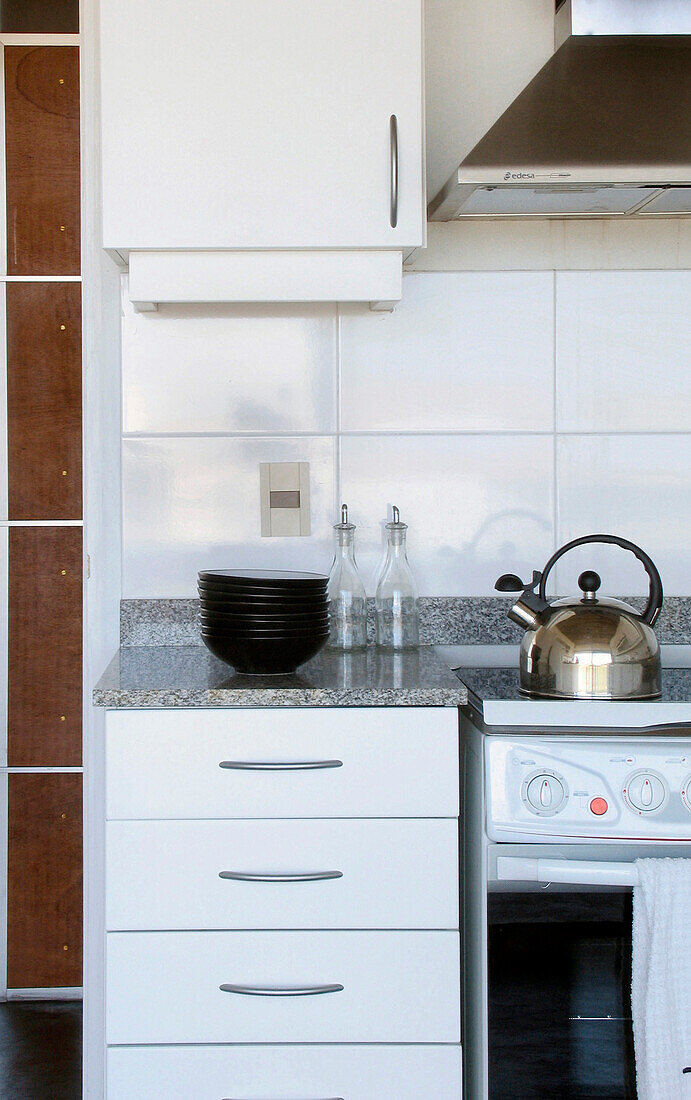 Silberner Wasserkocher auf Kochfeld mit Schalen auf Küchenarbeitsplatte
