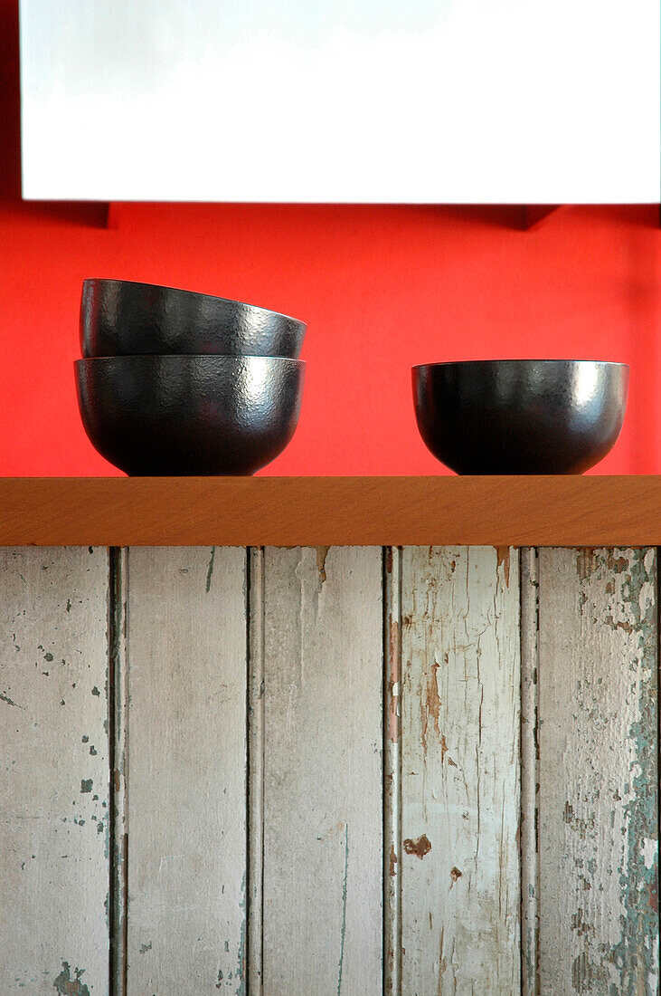 Schwarze Schalen auf recyceltem Küchentisch mit Lapacho-Platte und rot gestrichenen Wänden