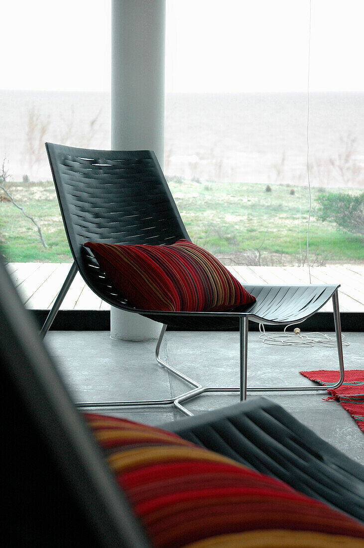 Metal framed chair with striped cushion in window of beach house