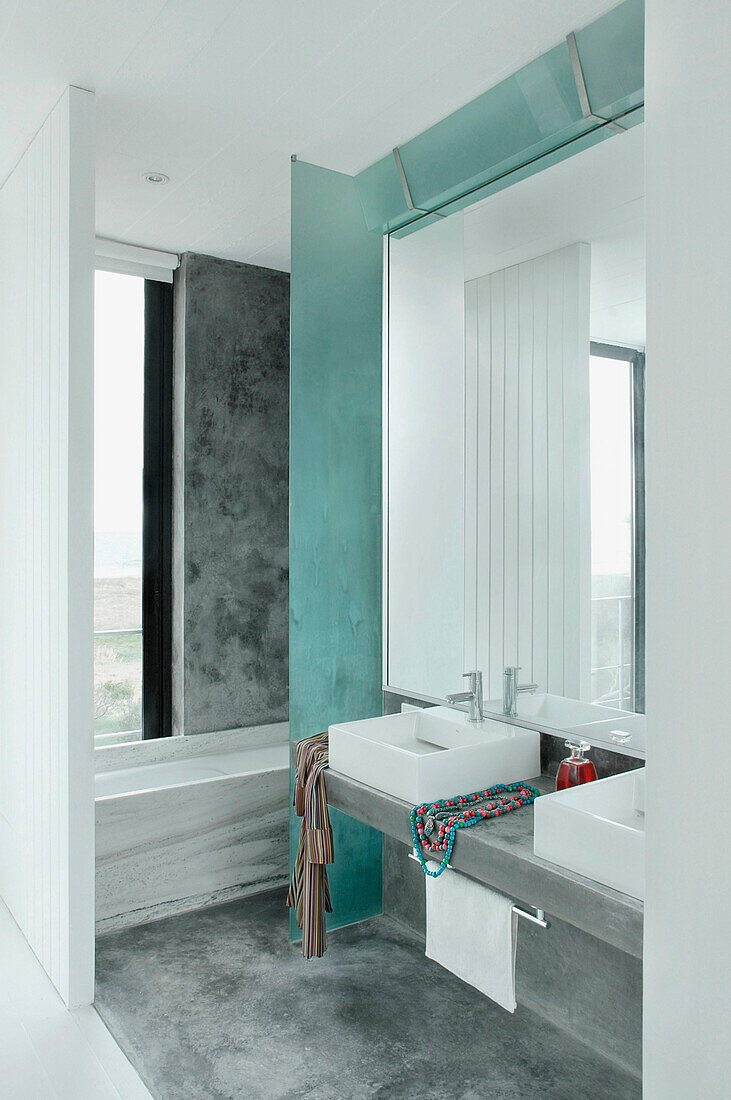 Badezimmer mit Betonboden und großem reflektierendem Spiegel
