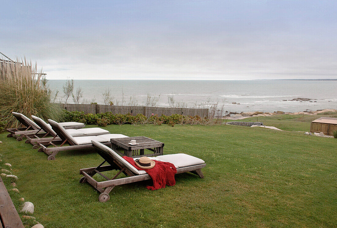 Sunloungers in beach house garden with view to sea